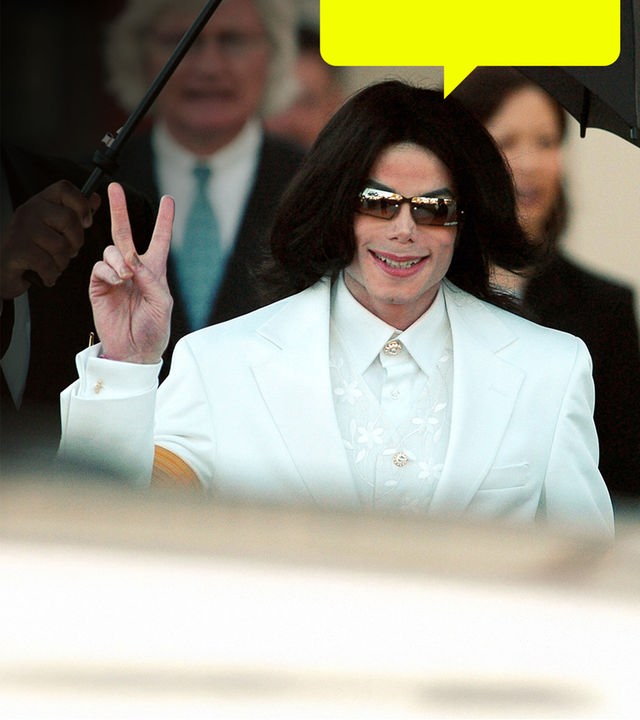 Micheal Jackson in weißem Anzug auf dem Weg zum Gericht, zeigt mit der rechten hand das Peace-Zeichen
