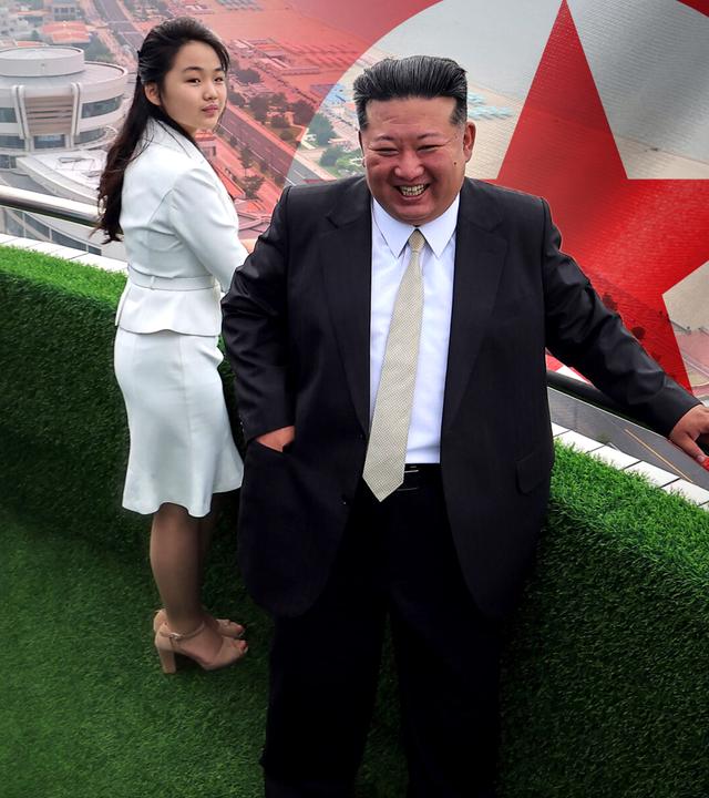 Kim Jong Un und seine Tocher Ju-Ae bei der Eröffnung eines Touristenresorts an der Küste Nordkoreas im Jahr 2025; im Hintergrund groß die Flagge von Nordkorea