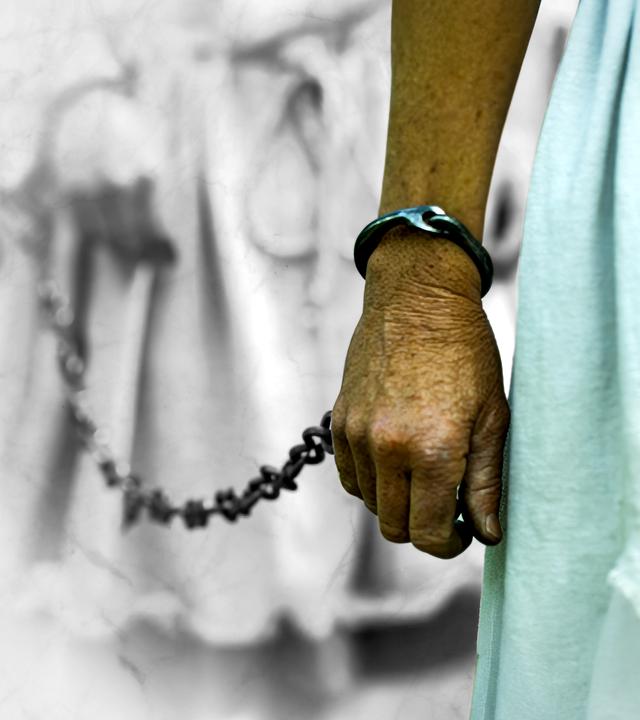 Frau mit Tunika, Nahaufnahme Taille/Hüfte. Die Frau liegt in Ketten. Im Hintergrund