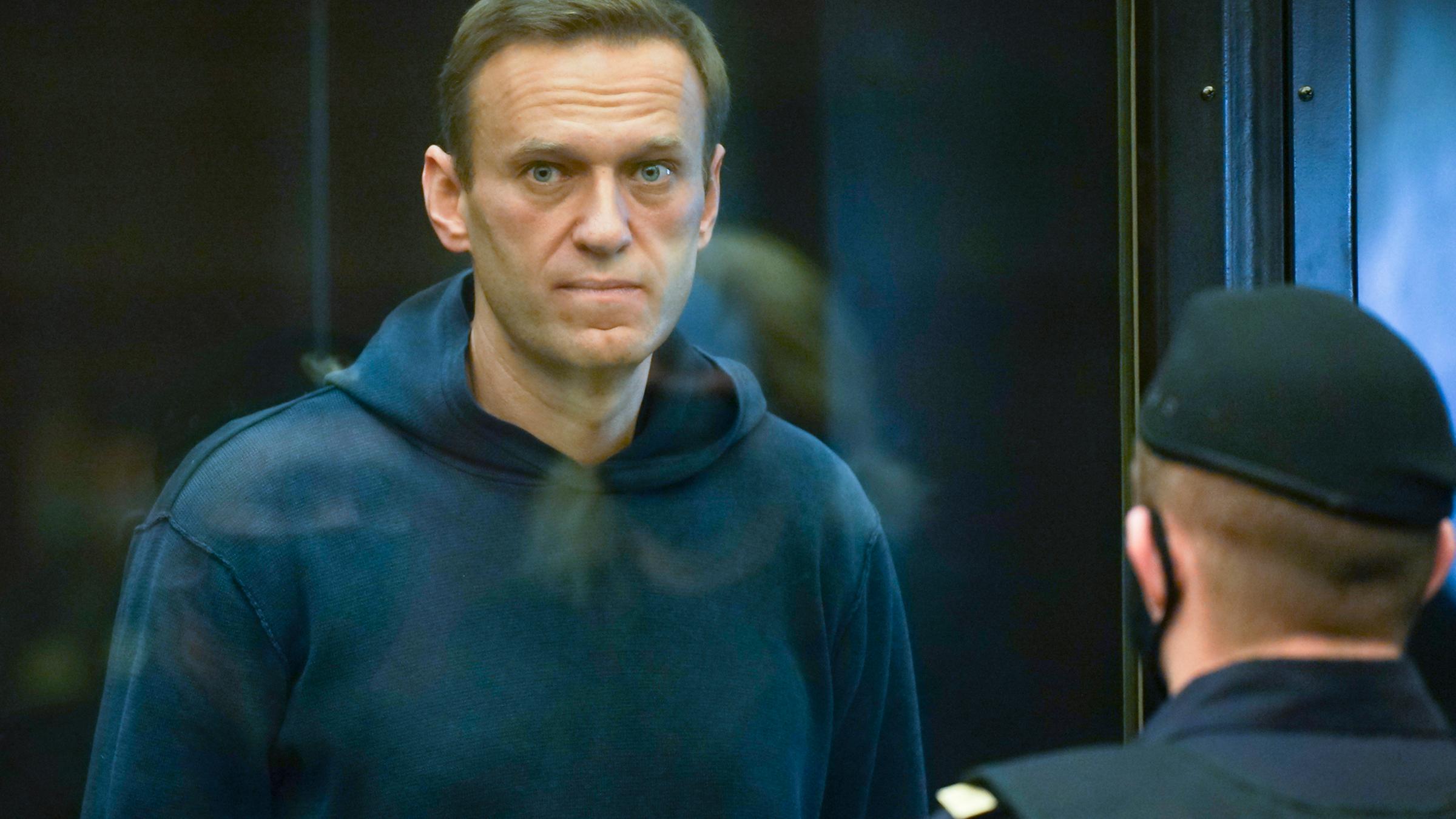 Der russische Oppositionsführer Alexej Nawalny steht im Gericht im Käfig während einer Anhörung. Vor ihm ein Polizist.