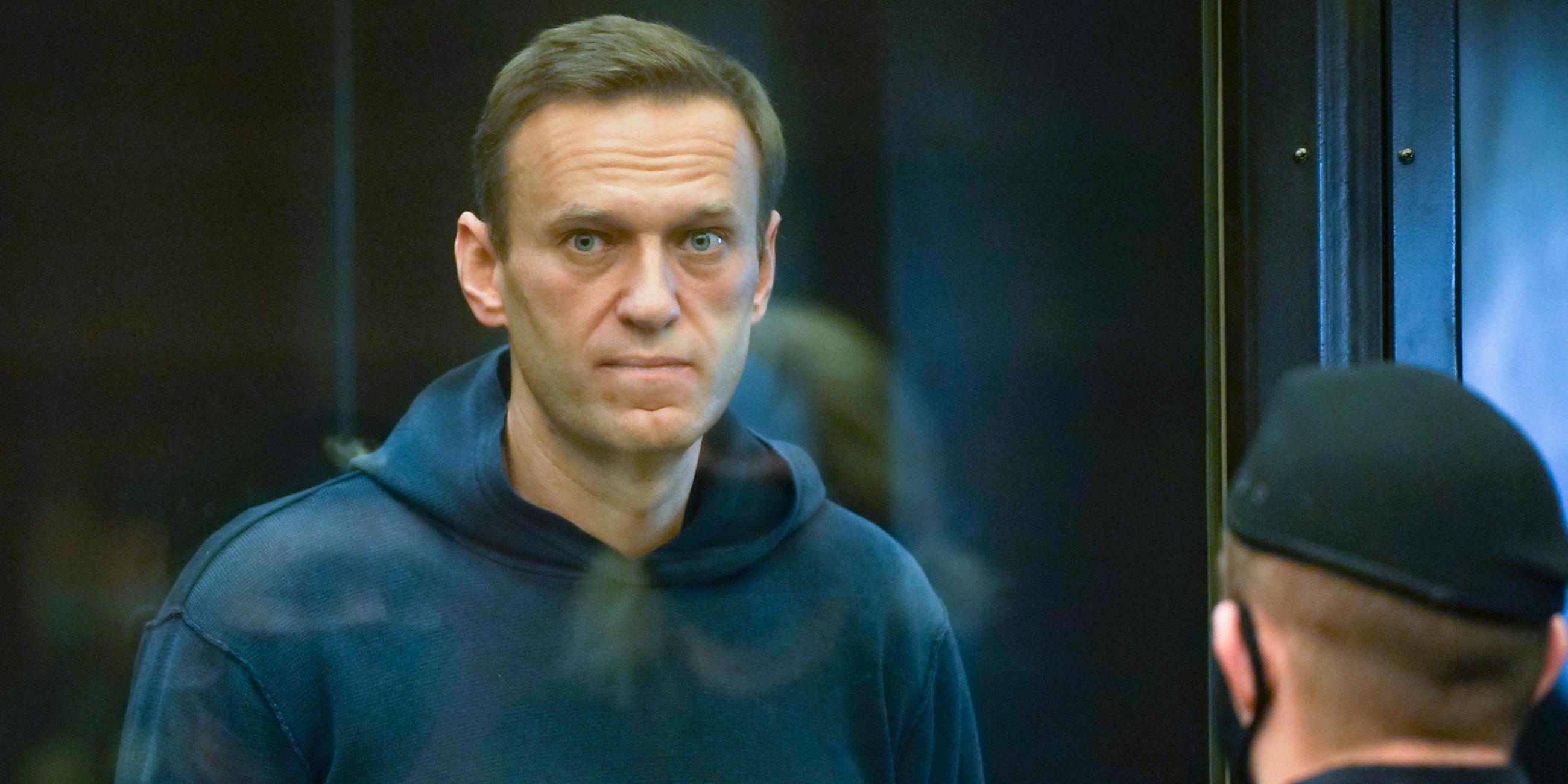 Der russische Oppositionsführer Alexej Nawalny steht im Gericht im Käfig während einer Anhörung. Vor ihm ein Polizist.