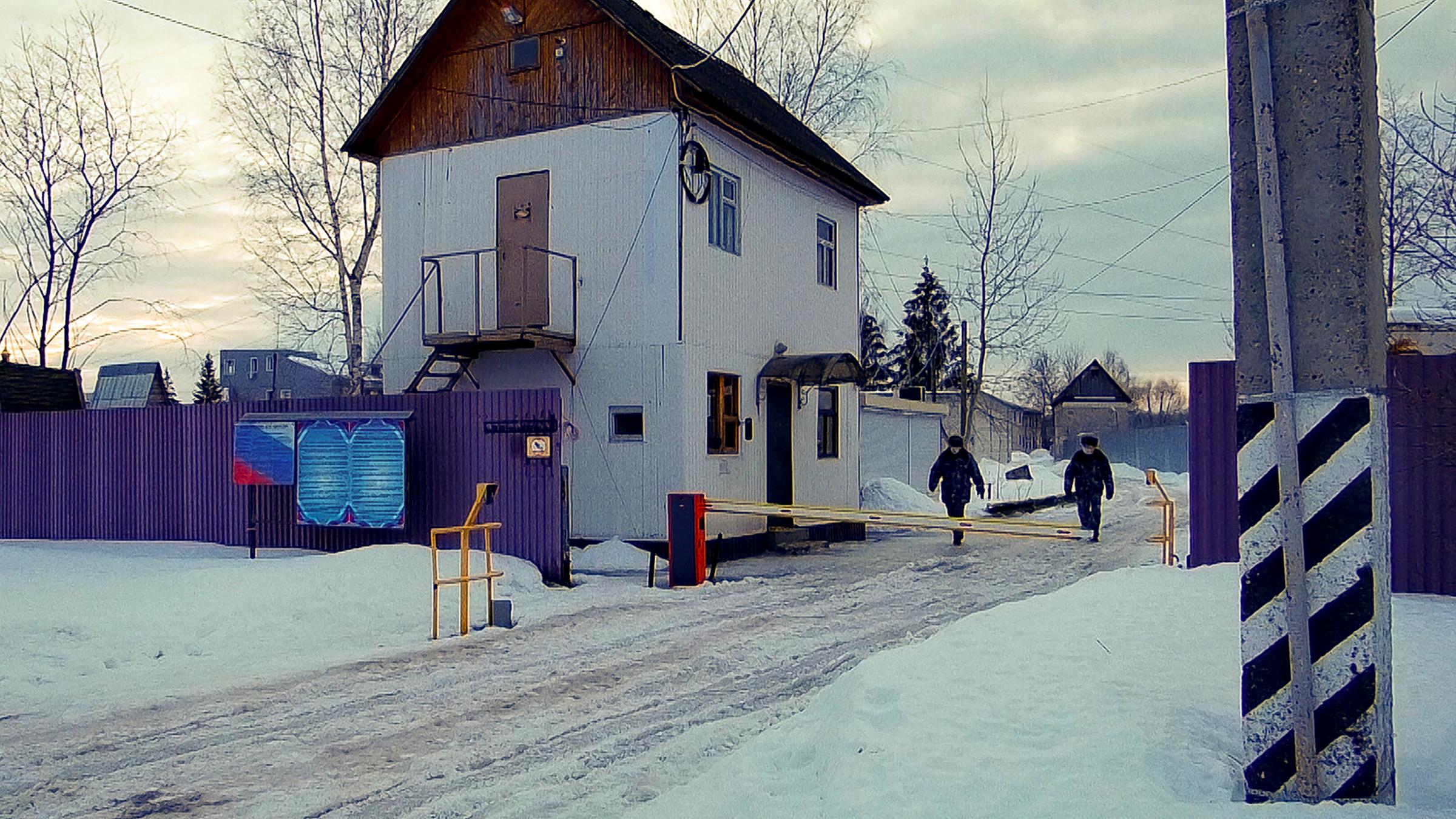 Hinter einer Schranke und einem Zaun ist ein Haus zu erkennen. Es handelt sich um das Gelände des Straflagers, in dem der russische Oppositionelle Alexej Nawalny gefangen ist.