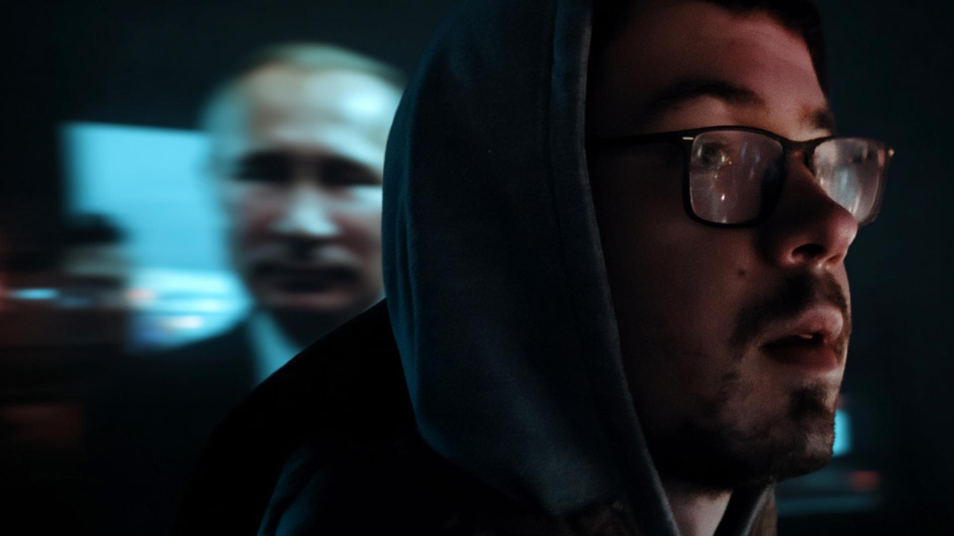 Eine Kollage mit zwei Gesichtern. Rechts im Vordergrund ein Mann mit Brille und Bart, der nach rechtshalboben schaut. Links und verschwommen Putins Gesicht.