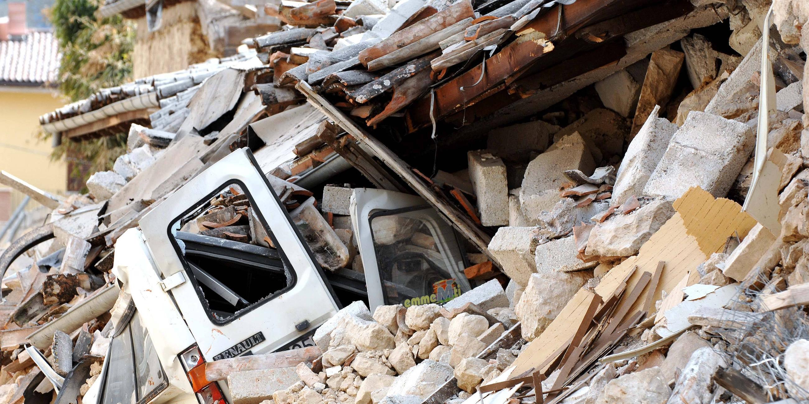 Ein Auto ist unter den Trümmern eines eingestürzten Hauses in L'Aquila begraben