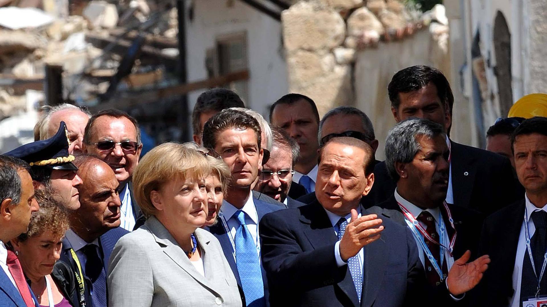 Angela Merkel und Premierminister Silvio Berlusconi besichtigen die Erdbebenschäden in Onna am Rande des G8-Gipfels in L'Aquila