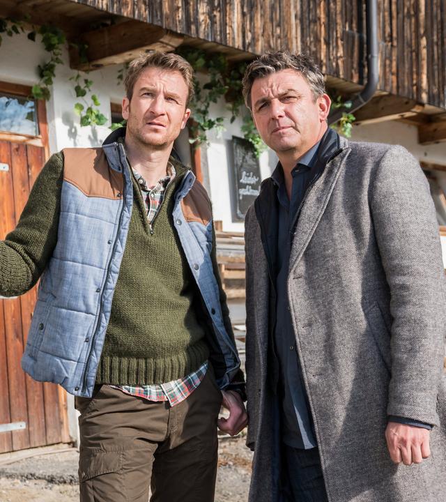 "Der Bergdoktor: Zeit der Wölfe (1)": Hans Gruber (Heiko Ruprecht) und Dr. Martin Gruber (Hans Sigl) stehen nebeneinander auf dem Hof und blicken nachdenklich in die Ferne.