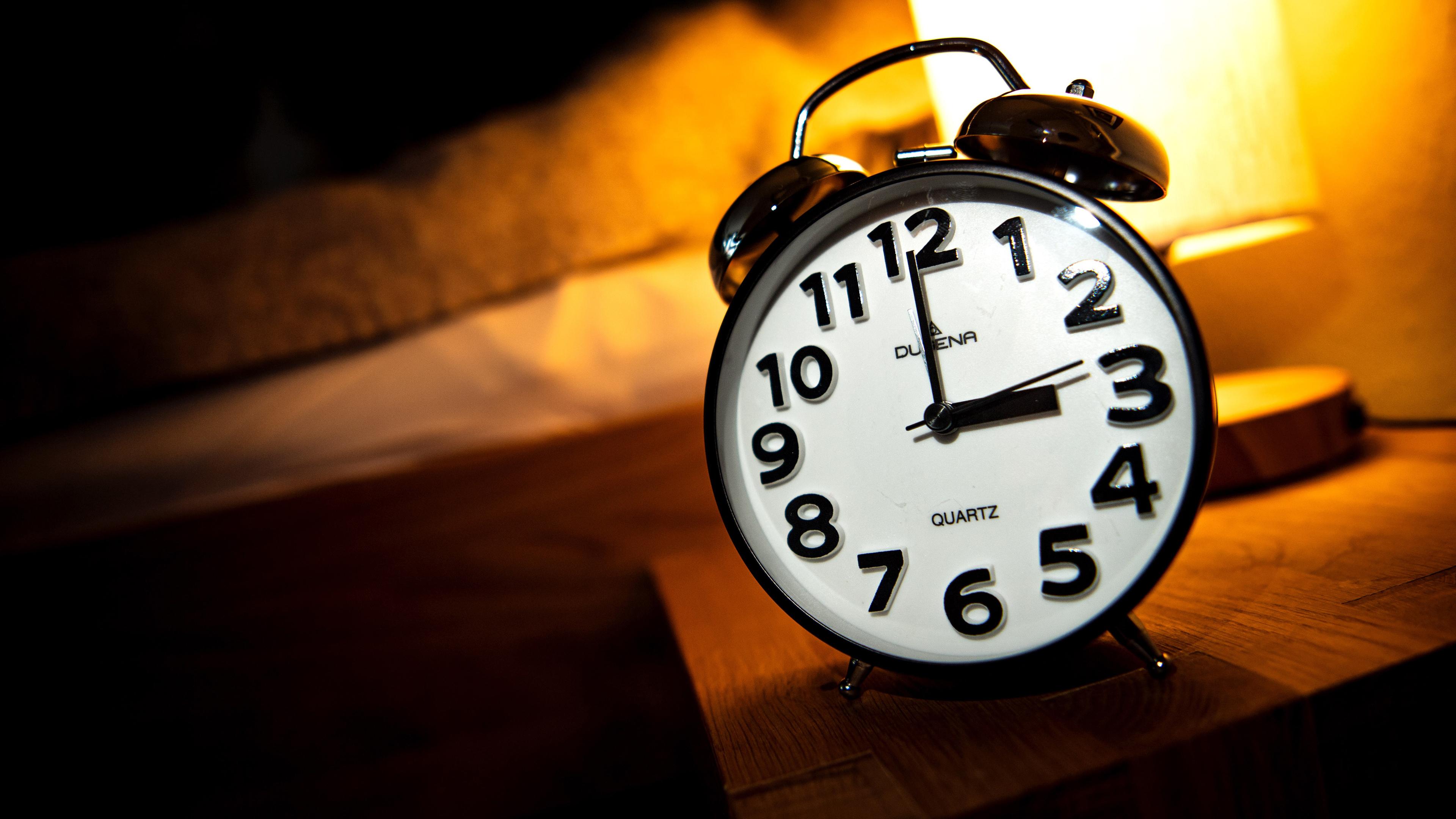 Ein Wecker steht auf einem Nachttisch