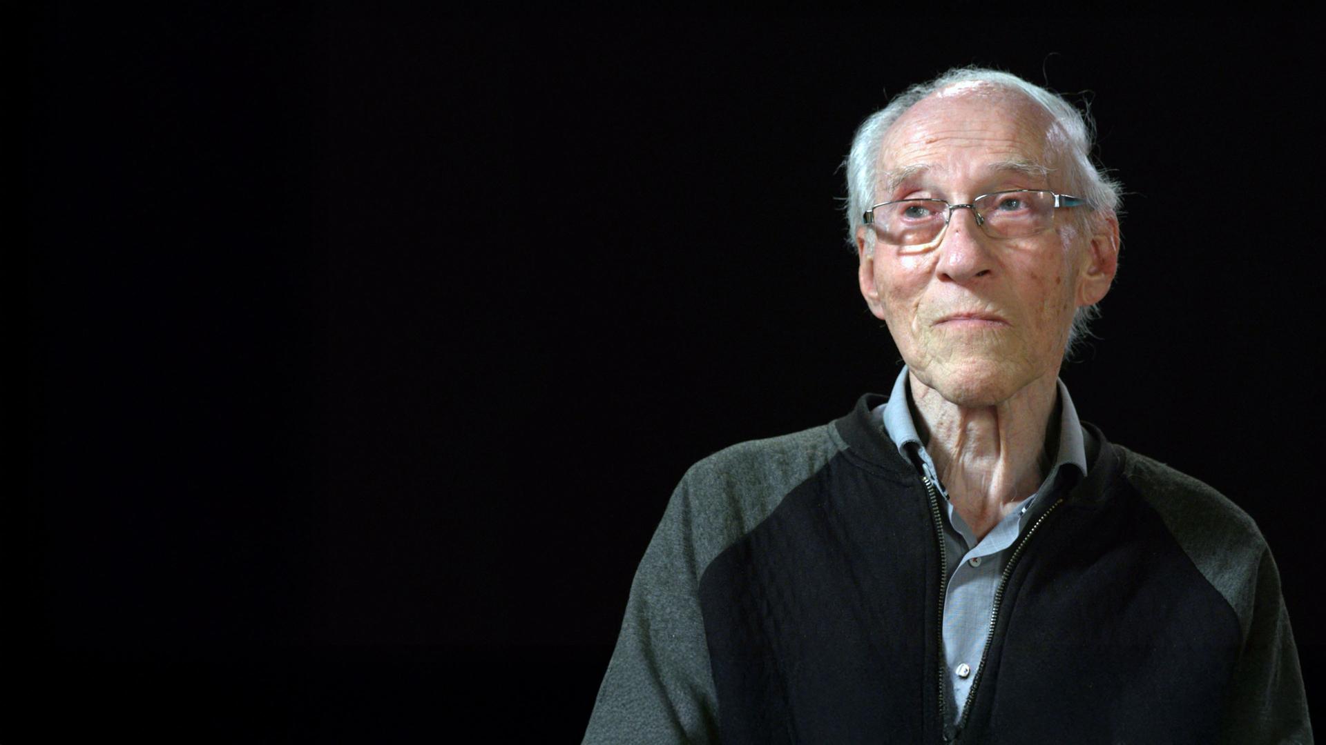 Henryk Joachims sitzt vor einem schwarzen Hintergrund 