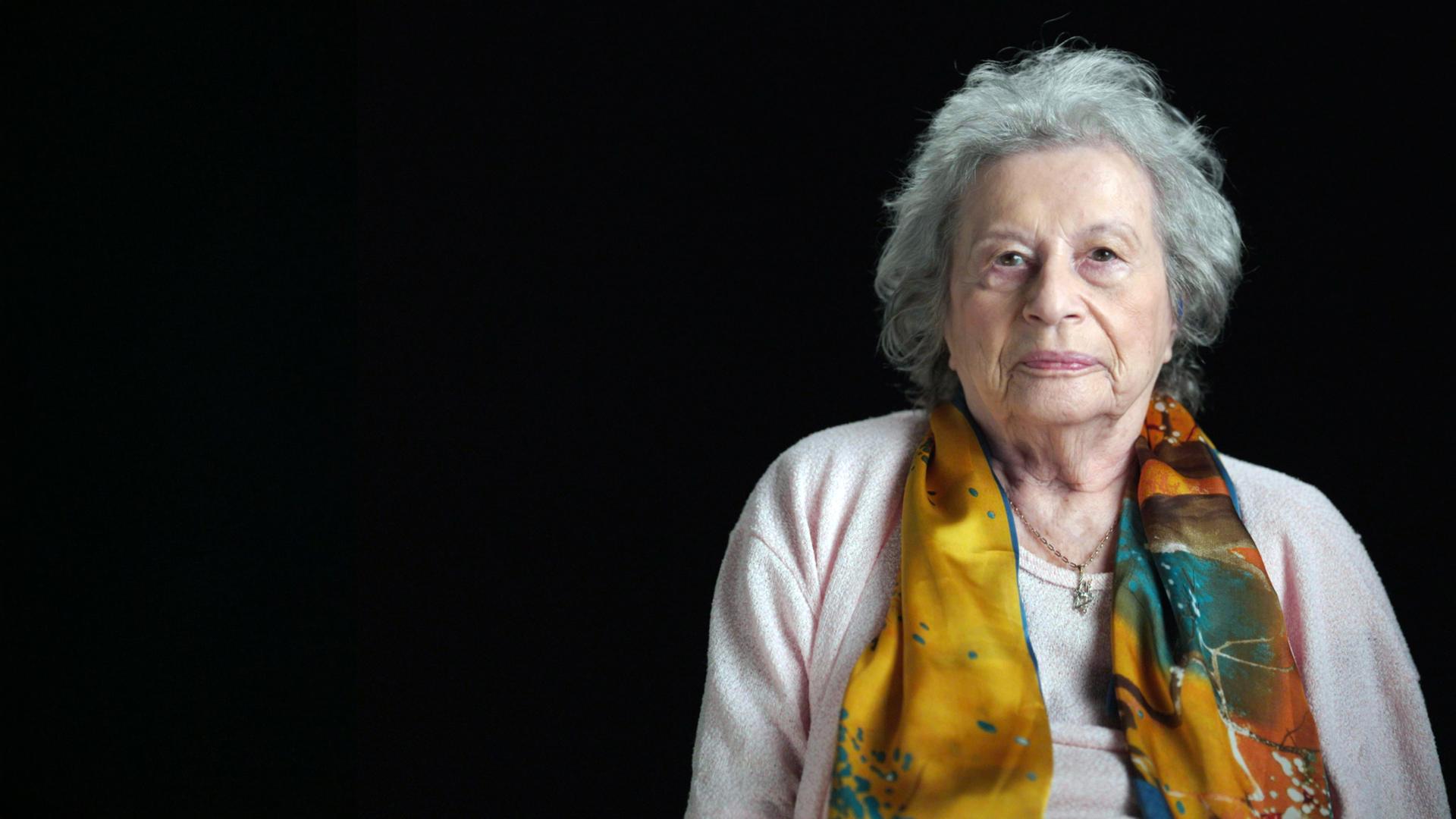 Tamar Dreifuss sitzt vor einem schwarzen Hintergrund.