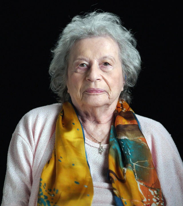 Tamar Dreifuss sitzt vor einem schwarzen Hintergrund.