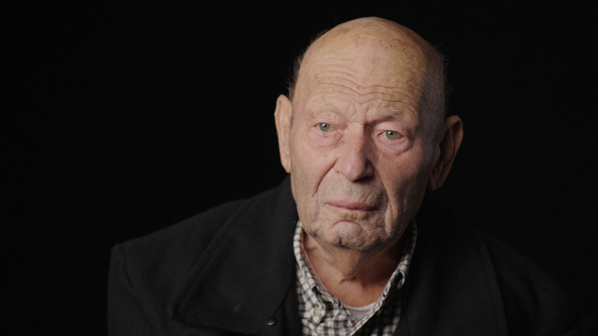 Leonid Vinderman sitzt vor einem schwarzen Hintergrund 