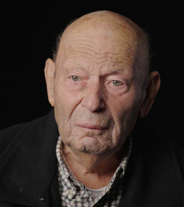 Leonid Vinderman sitzt vor einem schwarzen Hintergrund 