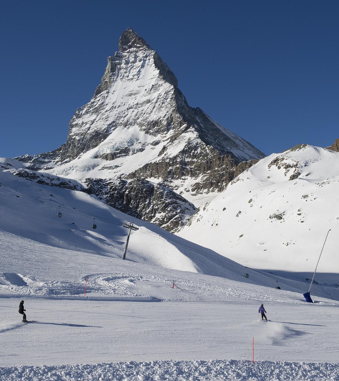 Skifahrer fahren die Pisten am Riffelberg mit dem Matterhorn im Hintergrund hinunter. 