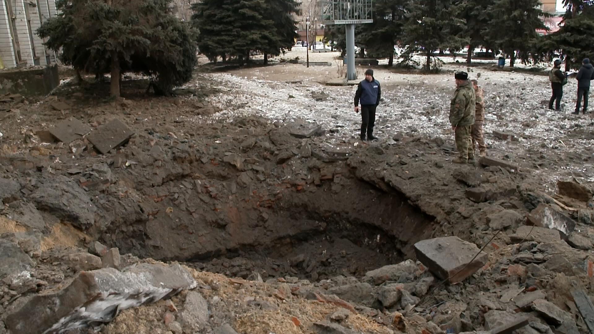 Menschen stehen am Rand eines Bombenkraters in Bachmut, Ostukraine