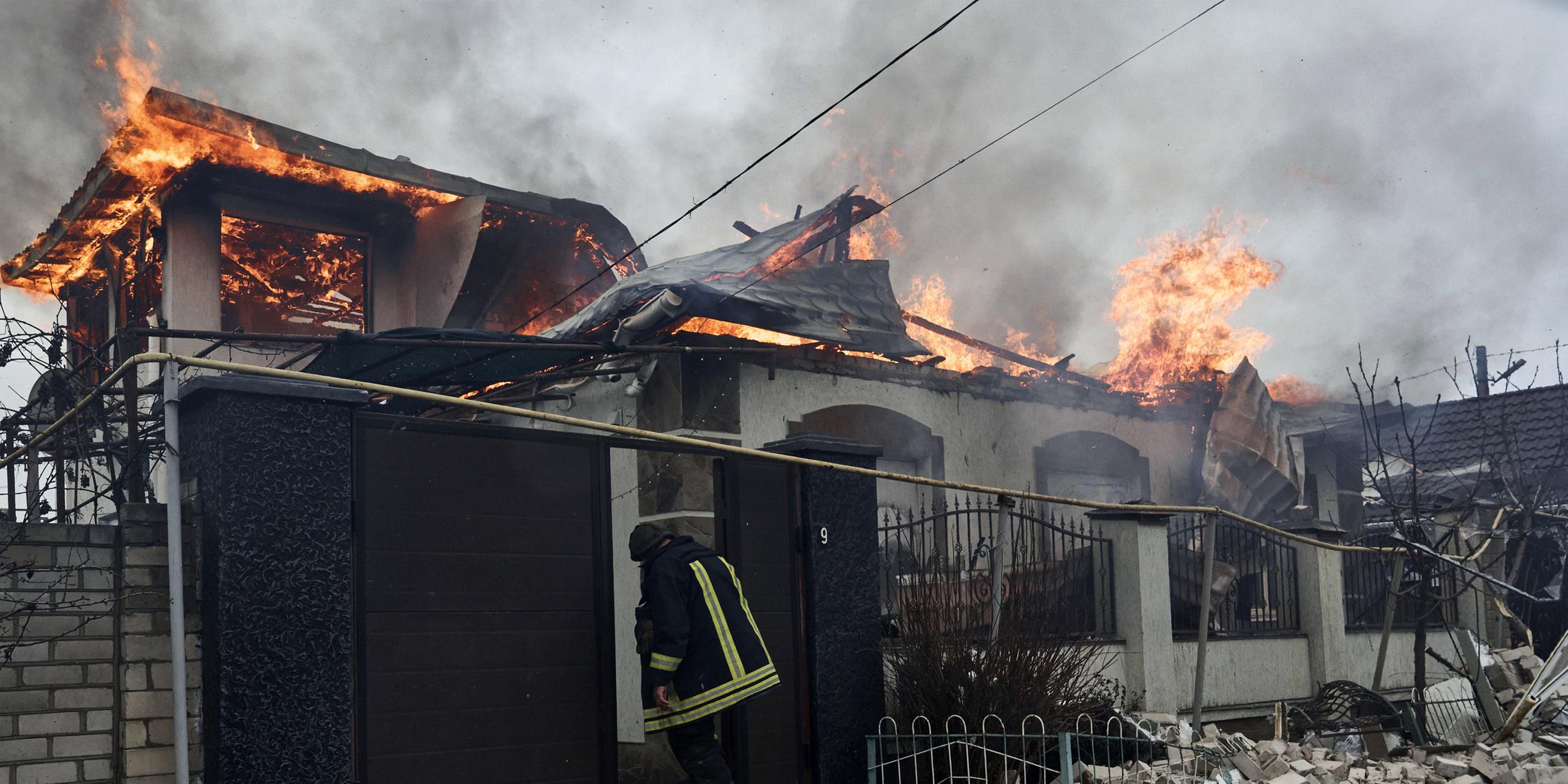 Ein Feuerwehrmann steht am orthodoxen Heiligabend, Freitag, den 6. 1. 2023, vor einem brennenden Haus in Cherson, Ukraine, das vom russischen Beschuss getroffen wurde. 