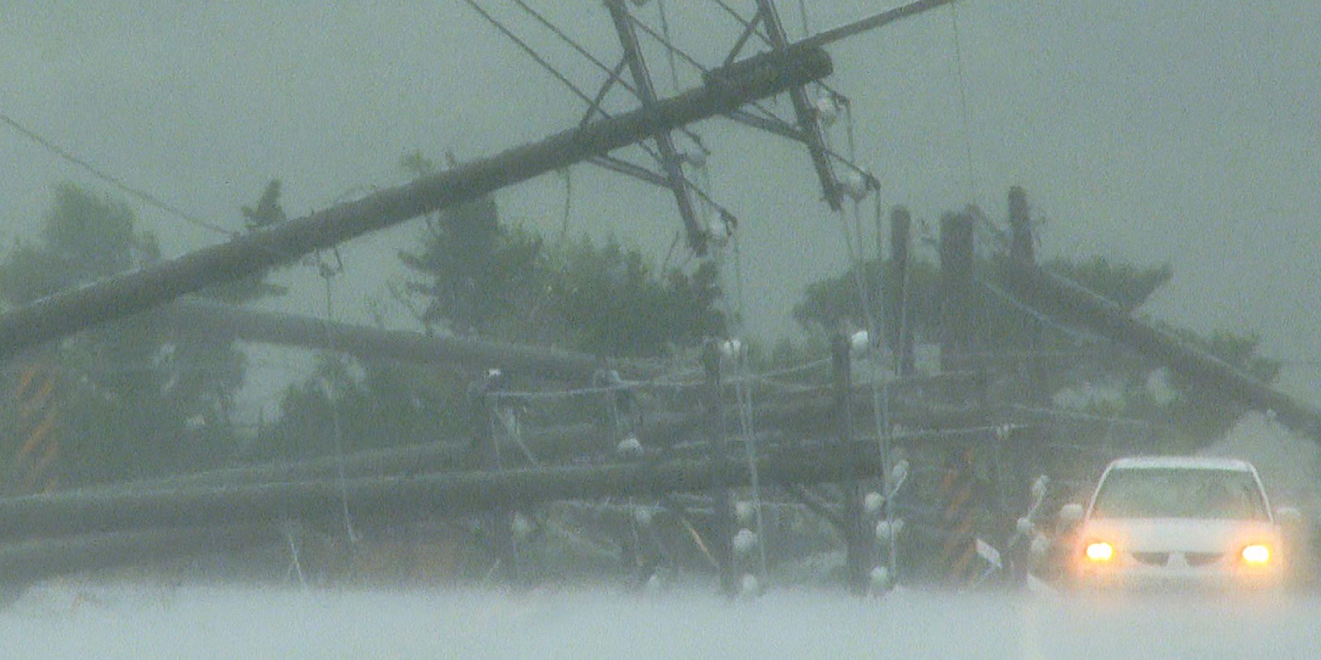 Ein Auto fährt am 5. Oktober 2023 an Stromleitungen vorbei, die durch die starken Winde des Taifuns Koinu im südlichen Landkreis Pingtung in Taiwan zerstört wurden.