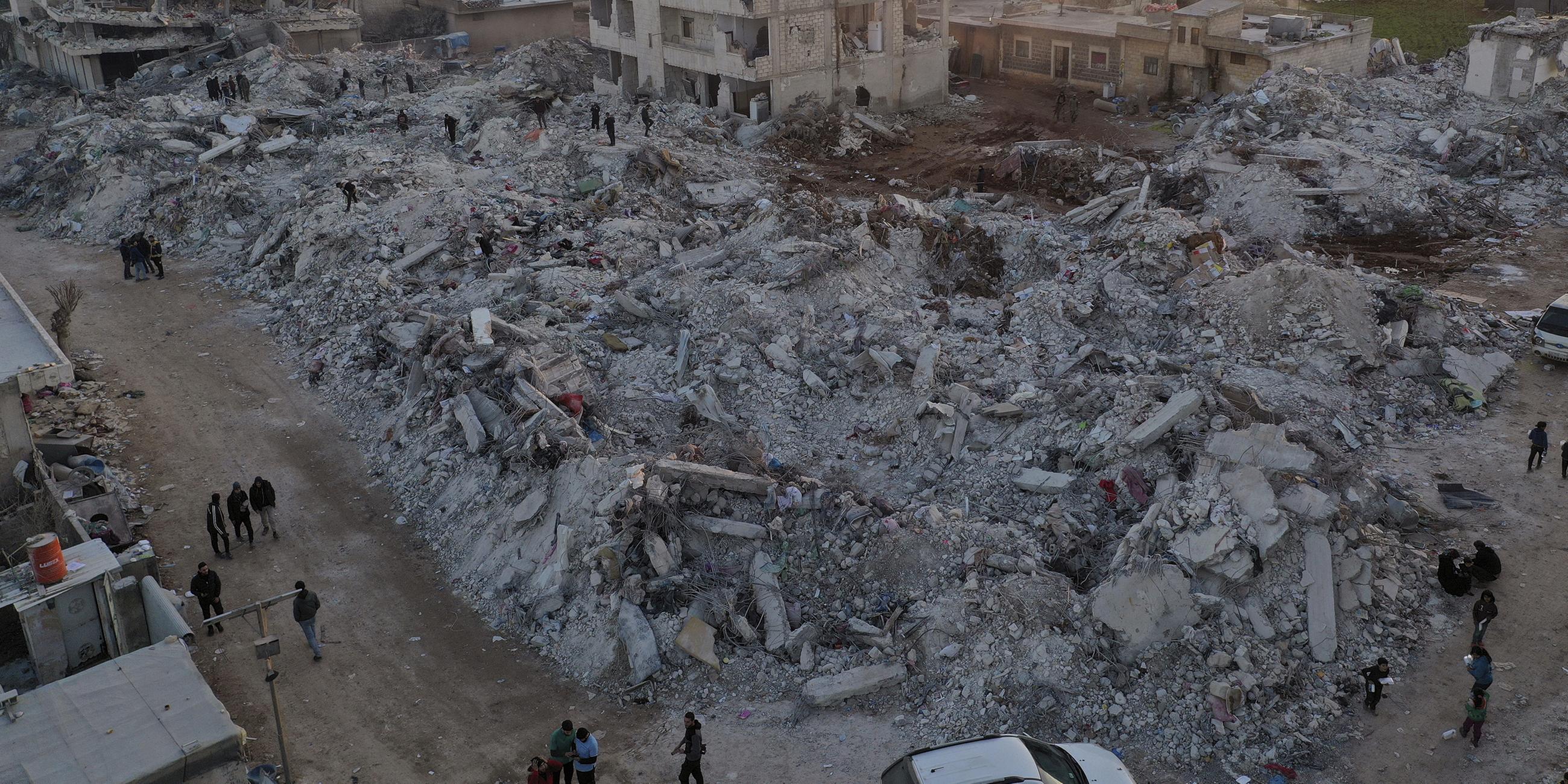Menschen gehen nach einem verheerenden Erdbeben in der Stadt Jinderis, Provinz Aleppo, Syrien, am 9. 2. 2023, an eingestürzten Gebäuden vorbei. 