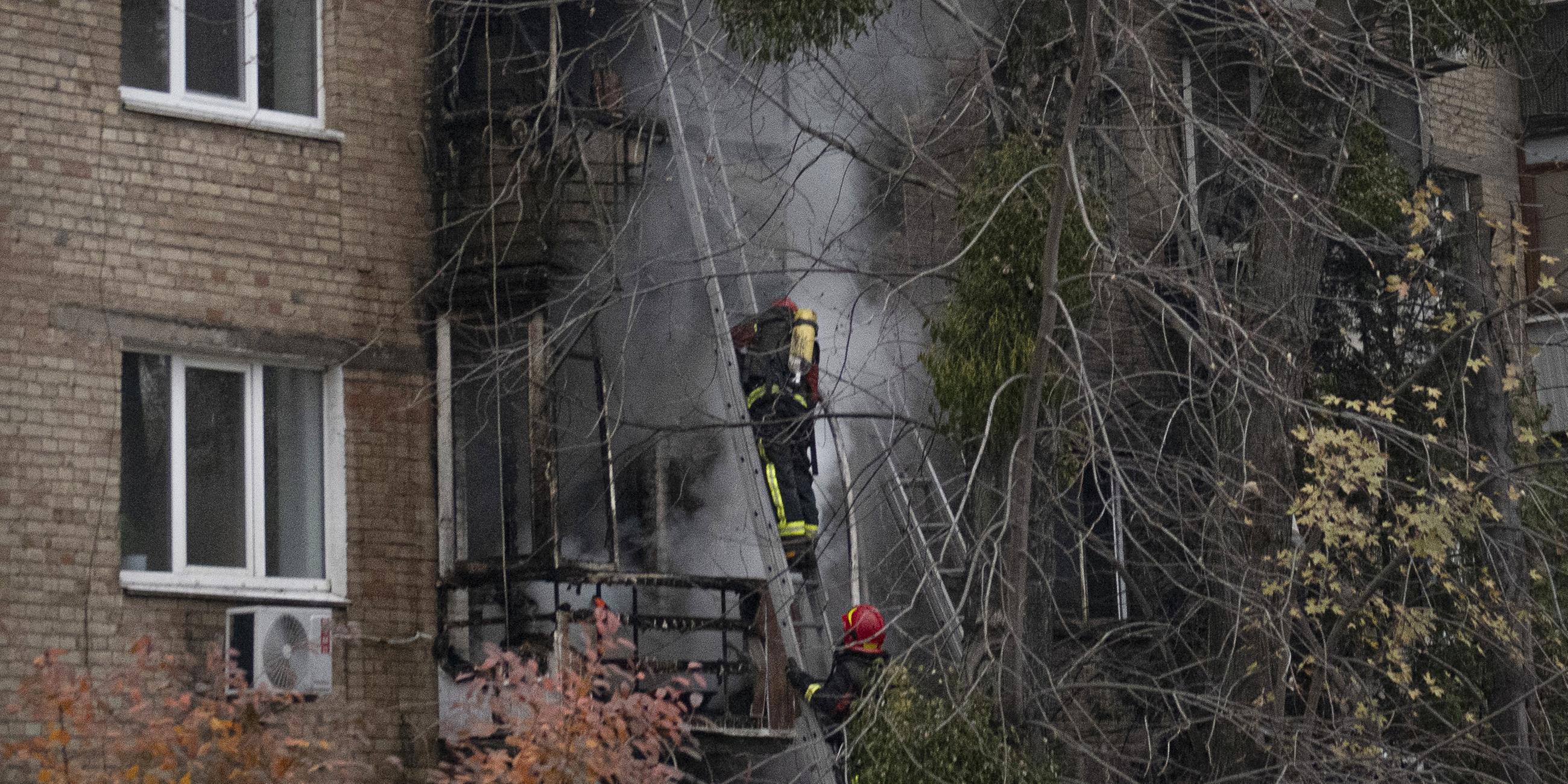 Feuerwehrleute des ukrainischen staatlichen Rettungsdienstes arbeiten am Dienstag, den 15. 11. 2022, am Ort eines russischen Beschusses in Kiew, Ukraine, um ein Feuer zu löschen. 