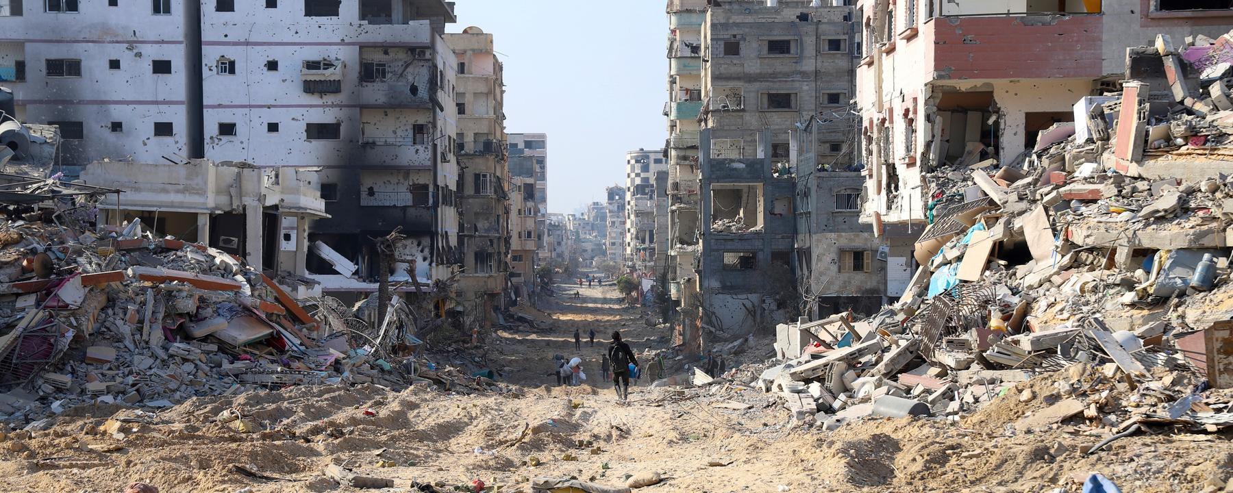 Palästinenser gehen zwischen den Überresten zerstörter Gebäude nach dem israelischen Bombardement auf der Hauptstraße von Gaza-Stadt am 2.1.2024.