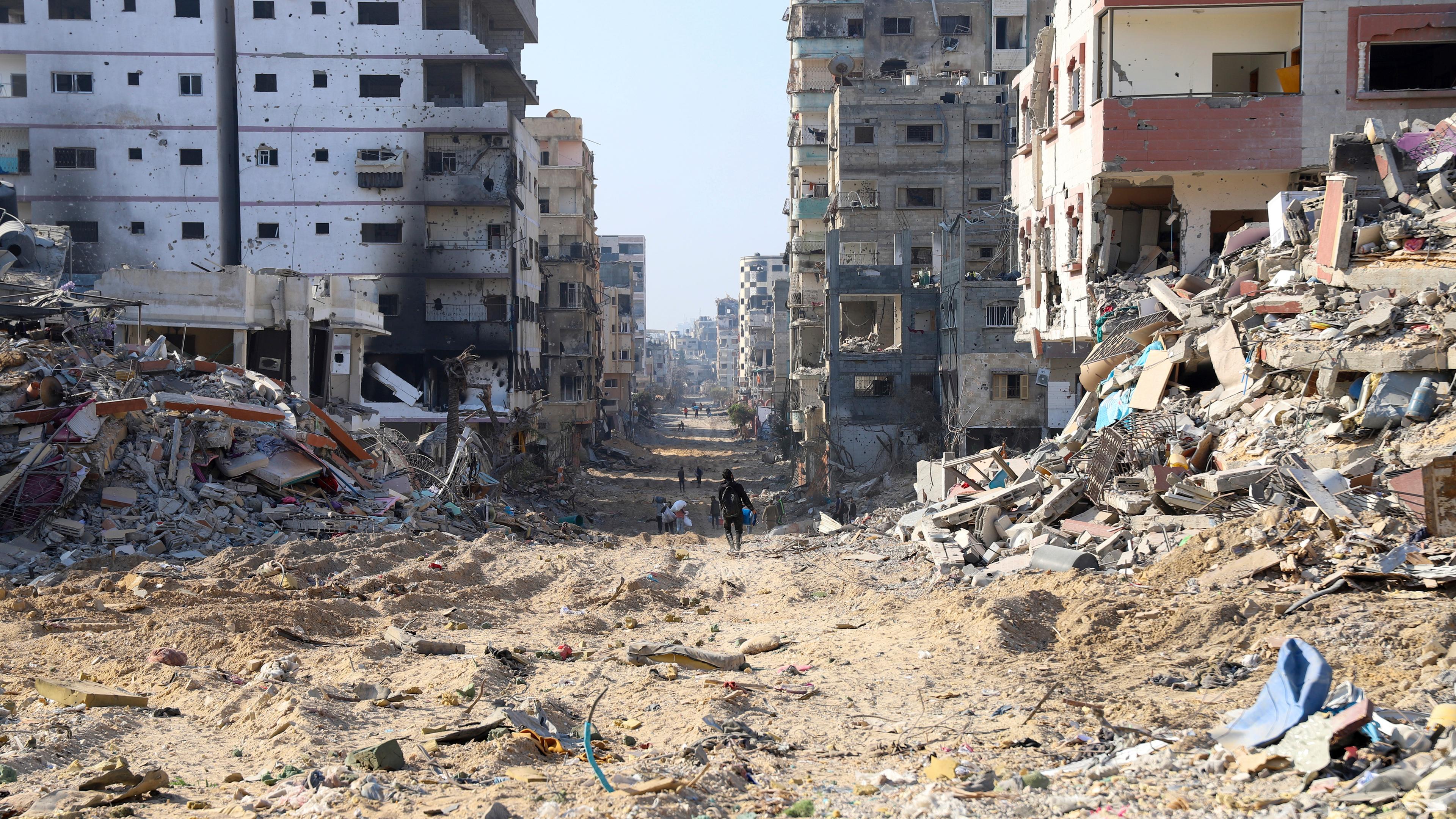 Palästinenser gehen zwischen den Überresten zerstörter Gebäude nach dem israelischen Bombardement auf der Hauptstraße von Gaza-Stadt am 2.1.2024.