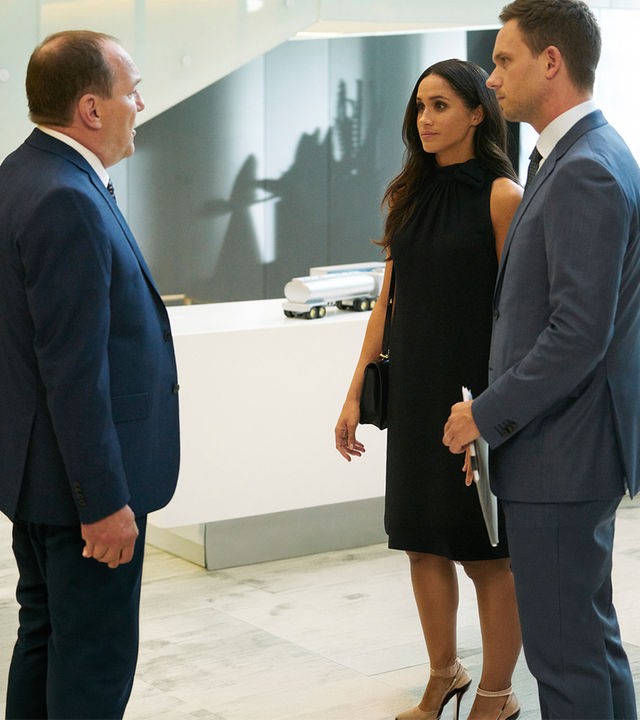"Suits - Zerwürfnis": Die in schwarz gekleidete Rachel (Meghan Markle) und Mike (Patrick J. Adams), der in seinen Händen ein Dokument hält,  hören konzentriert Larry Burnham (Larry Day) zu, der ihnen gegenübersteht.