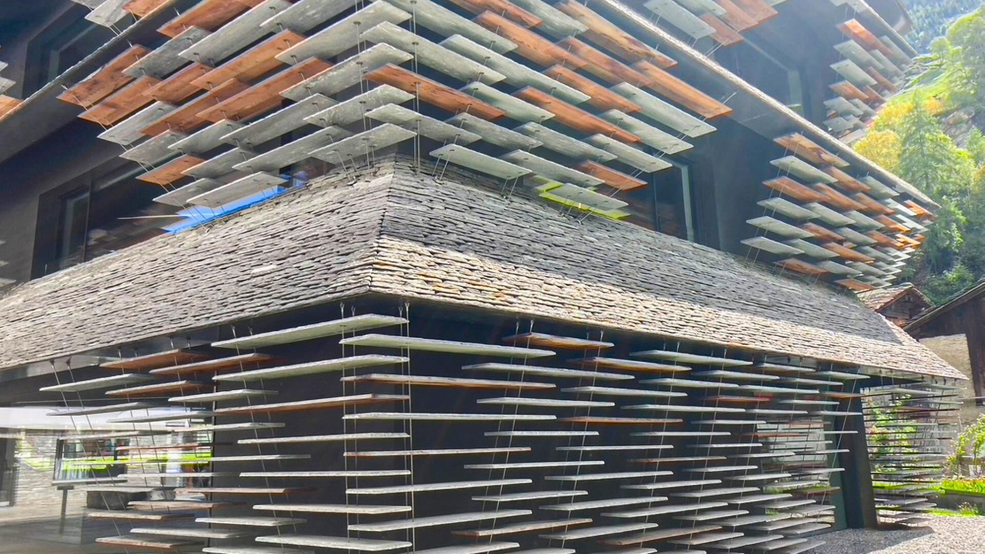 Geschäftshaus mit Fassade aus scheinbar schwebenden Steinplatten, die an Drahtseilen befestigt sind