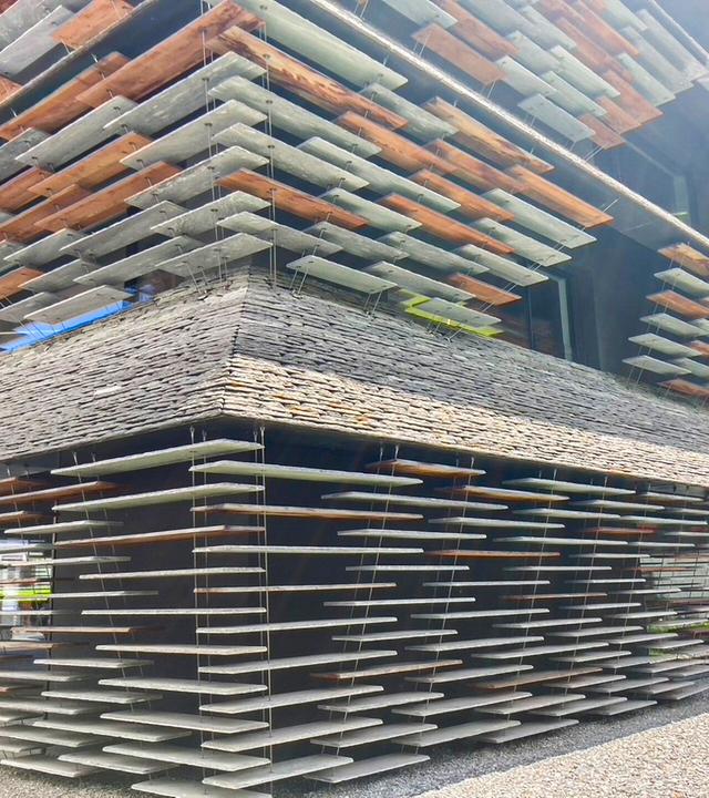 Geschäftshaus mit Fassade aus scheinbar schwebenden Steinplatten, die an Drahtseilen befestigt sind
