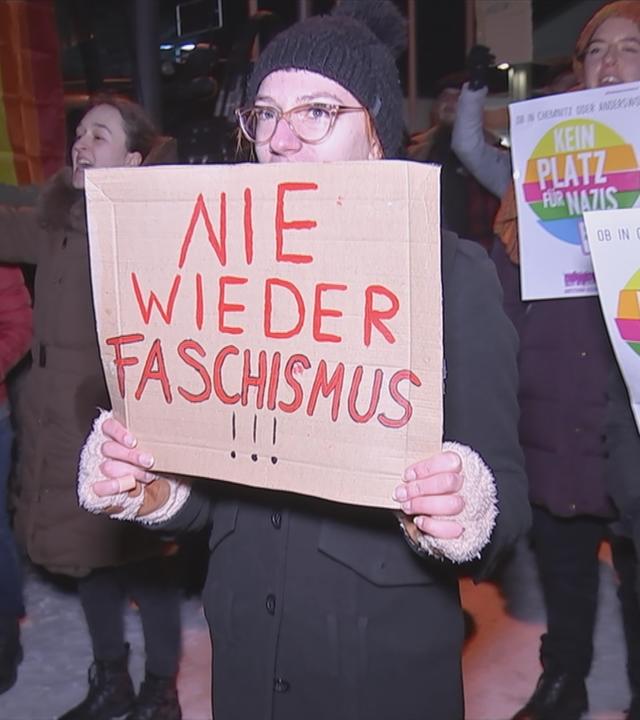 Auf dem Bild sieht man eine Frau die ein Plakat hochhebt auf dem steht: Nie wieder Faschismus.