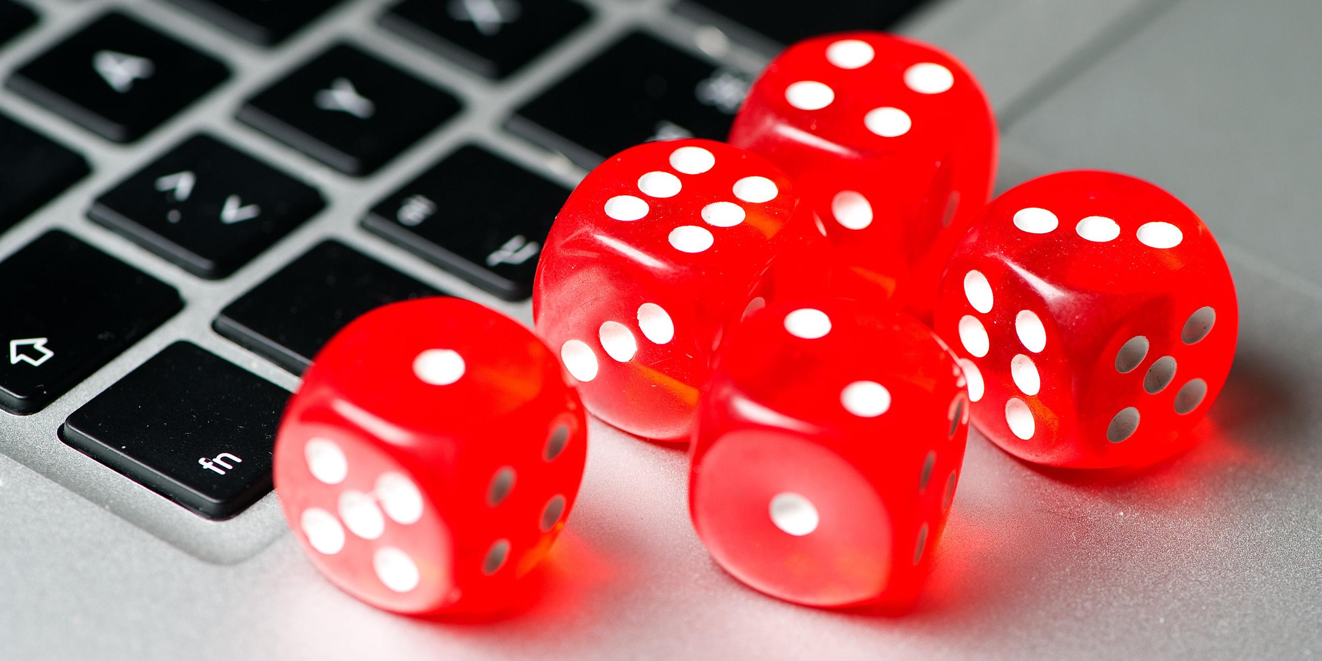 Symbolbild: rote Spielwürfel liegen auf der Tastatur eines Laptops