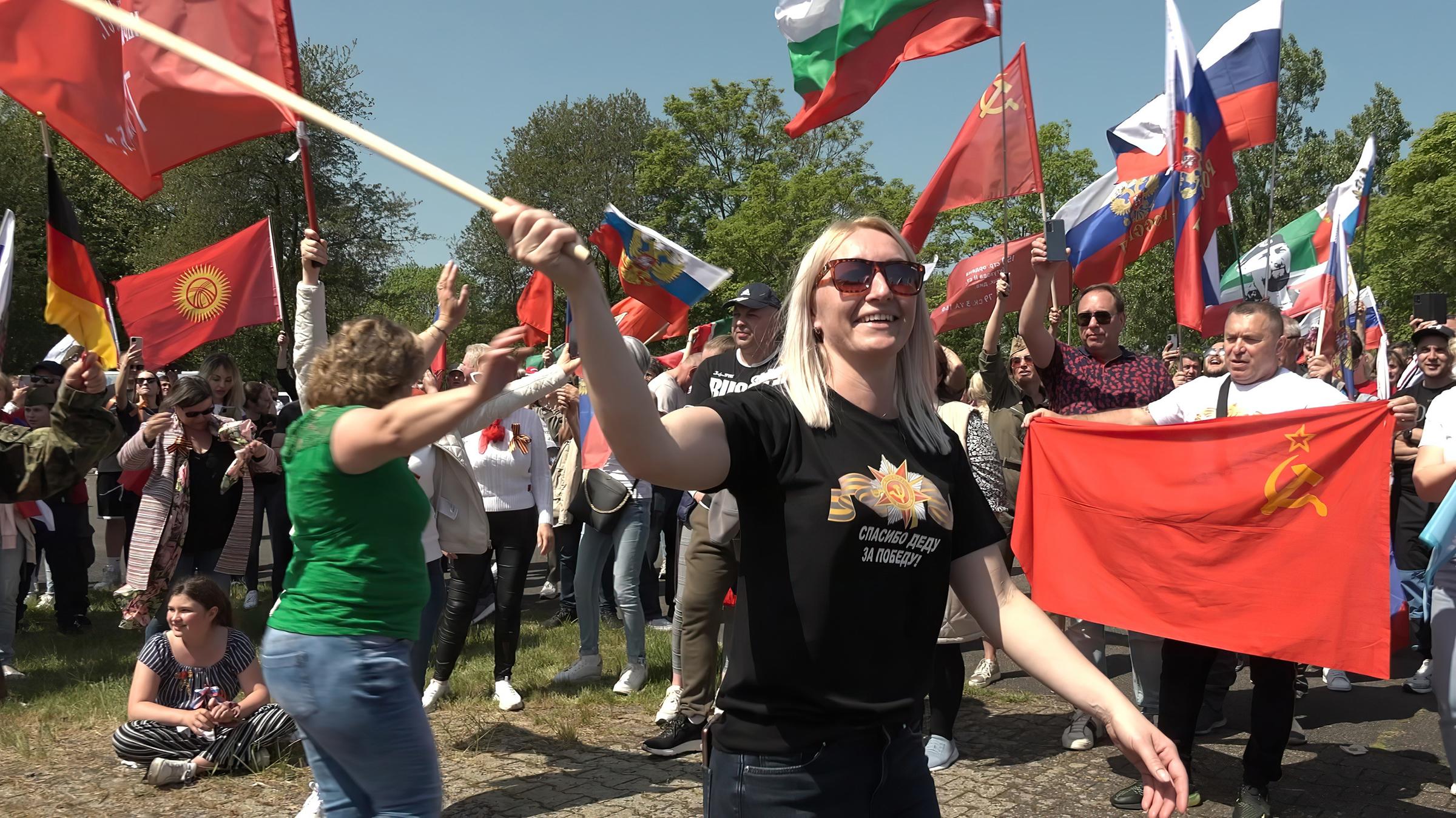 Aktivisten schwenken verschiedene Fahnen während einer Demonstration.