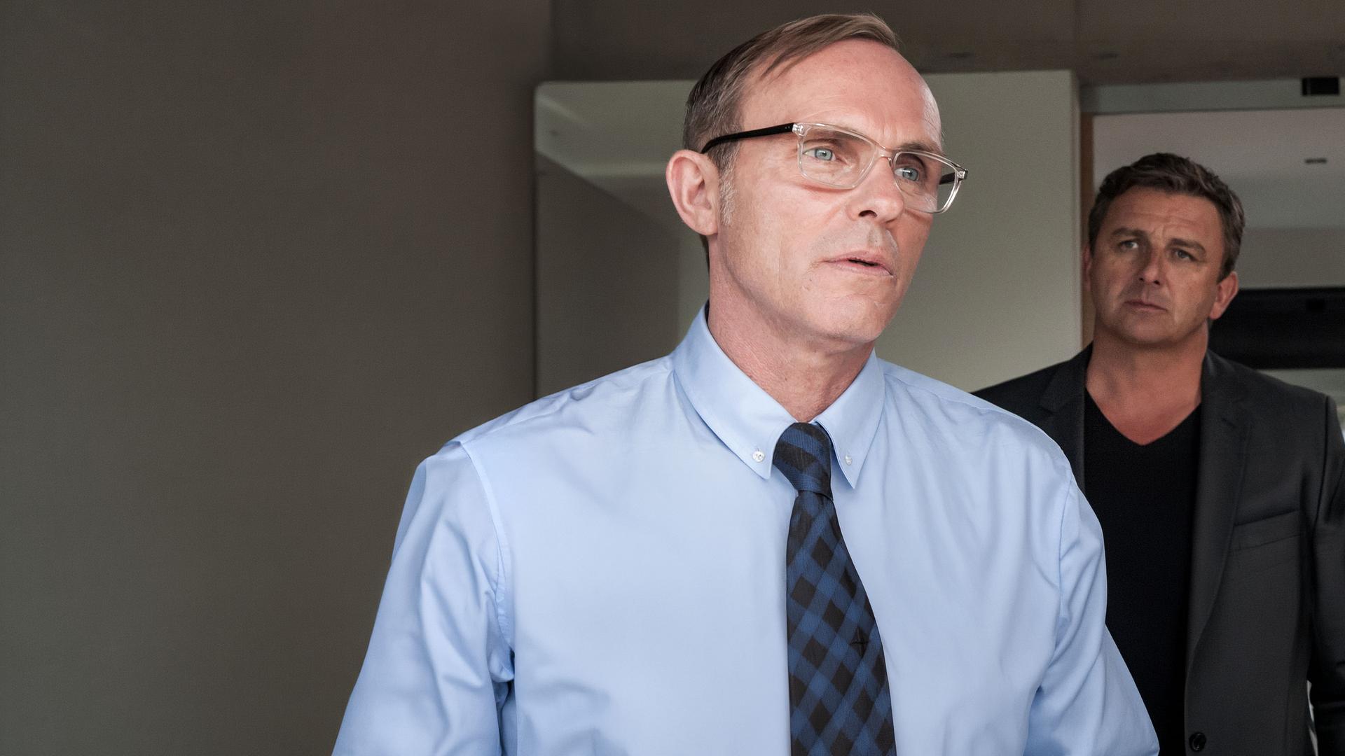 Martin Gruber (Hans Sigl) steht hinter Sebastian Lechner (Dirk Martens) in einem Zimmer.