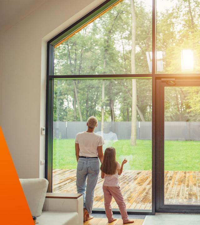 Familie schaut aus gro?em Fenster aus Wohnung in den Garten