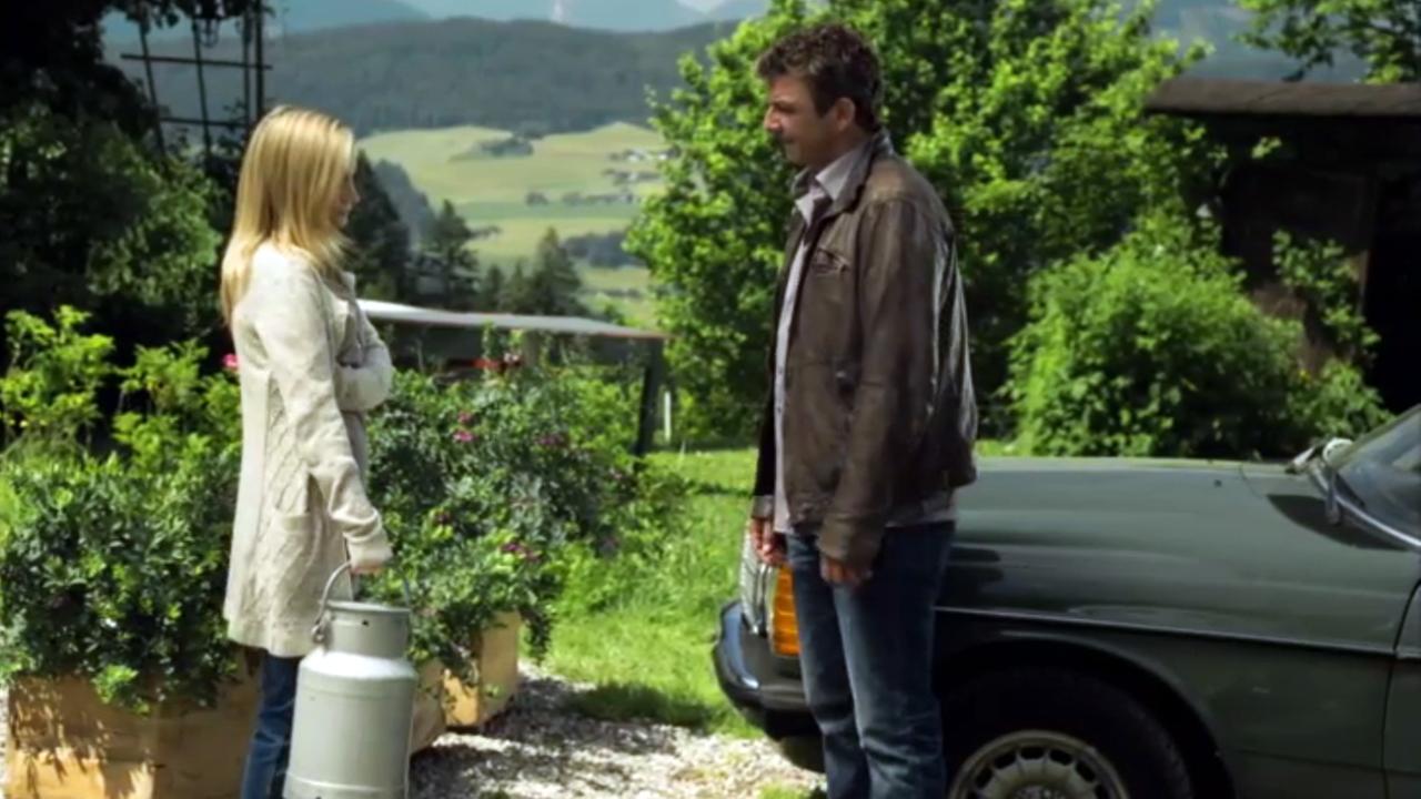 "Der Bergdoktor - Zwänge": Martin (Hans Sigl) und Hans (Heiko Ruprecht) stehen auf einem Feld und unterhalten sich. Im Hintergrund ein Traktor und das Bergpanorama.