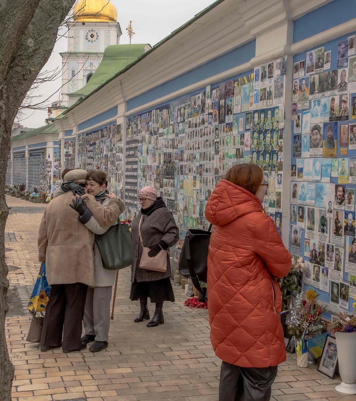 Friends embrace Liudmyla (L) who lost her son Tymofii Boyko, a Ukrainian soldier who was killed fighting Russian troops, as they stand next to the "Wall of Remembrance of the Fallen for Ukraine" in downtown Kyiv, on February 23, 2024, ahead of the second anniversary of Russia's invasion of Ukraine. 