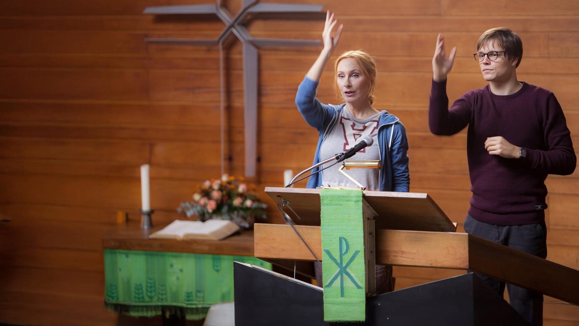 "Zwei verlorene Schafe": Thaddäus (Franz Hartwig) steht auf dem Trampolin und Rebecca (Andrea Sawatzki) daneben - im Hintergrund Fenster, Bücherregal und Stühle im Seminarraum.