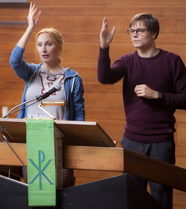 "Zwei verlorene Schafe": Thaddäus (Franz Hartwig) steht auf dem Trampolin und Rebecca (Andrea Sawatzki) daneben - im Hintergrund Fenster, Bücherregal und Stühle im Seminarraum.