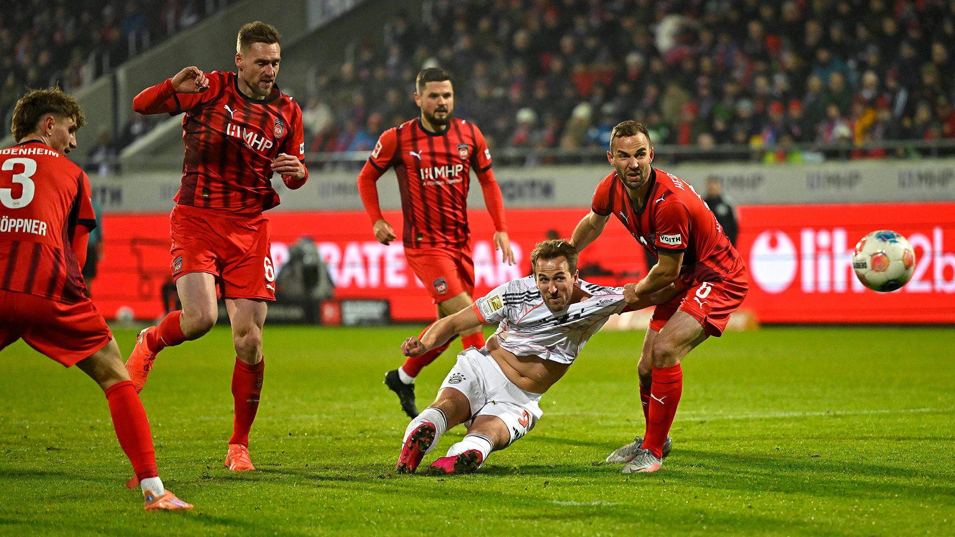 Im Zweikampf mit Heidenheims Benedikt Gimber geht Bayerns Stürmer Harry Kane nach einem Torschuss zu Boden