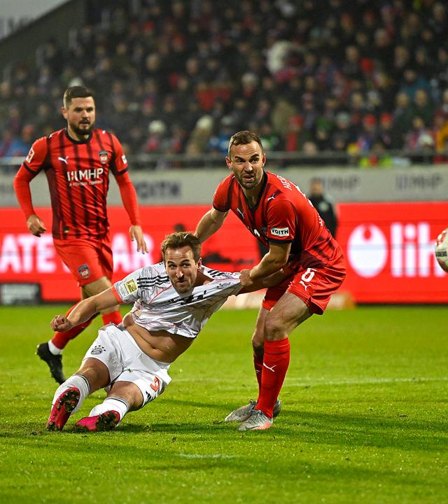 Im Zweikampf mit Heidenheims Benedikt Gimber geht Bayerns Stürmer Harry Kane nach einem Torschuss zu Boden