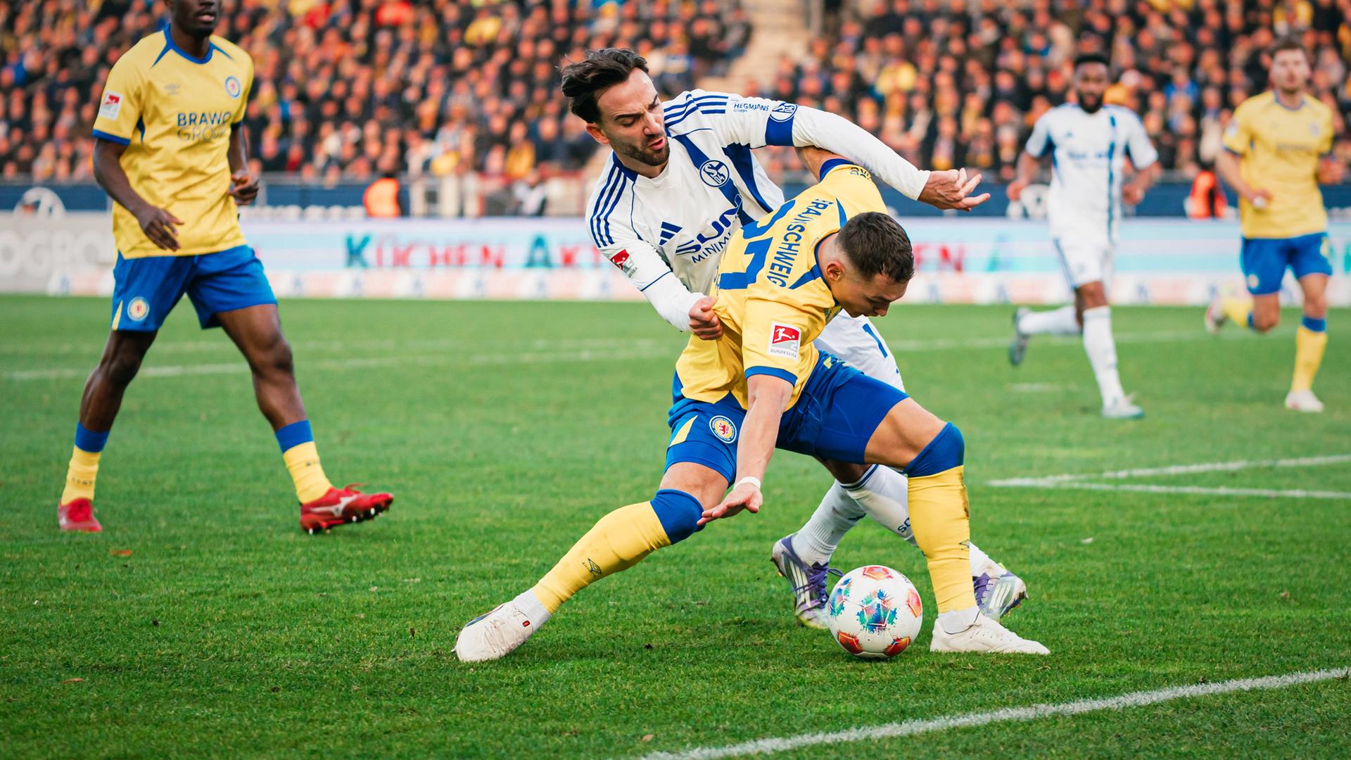 Braunschweigs Fabio Di Michele Sánchez wird in der Zweitligapartie zwischen der Eintracht aus Braunschweig und Schalke 04 von seinem Gegenspieler Karaman von hinten bedrängt