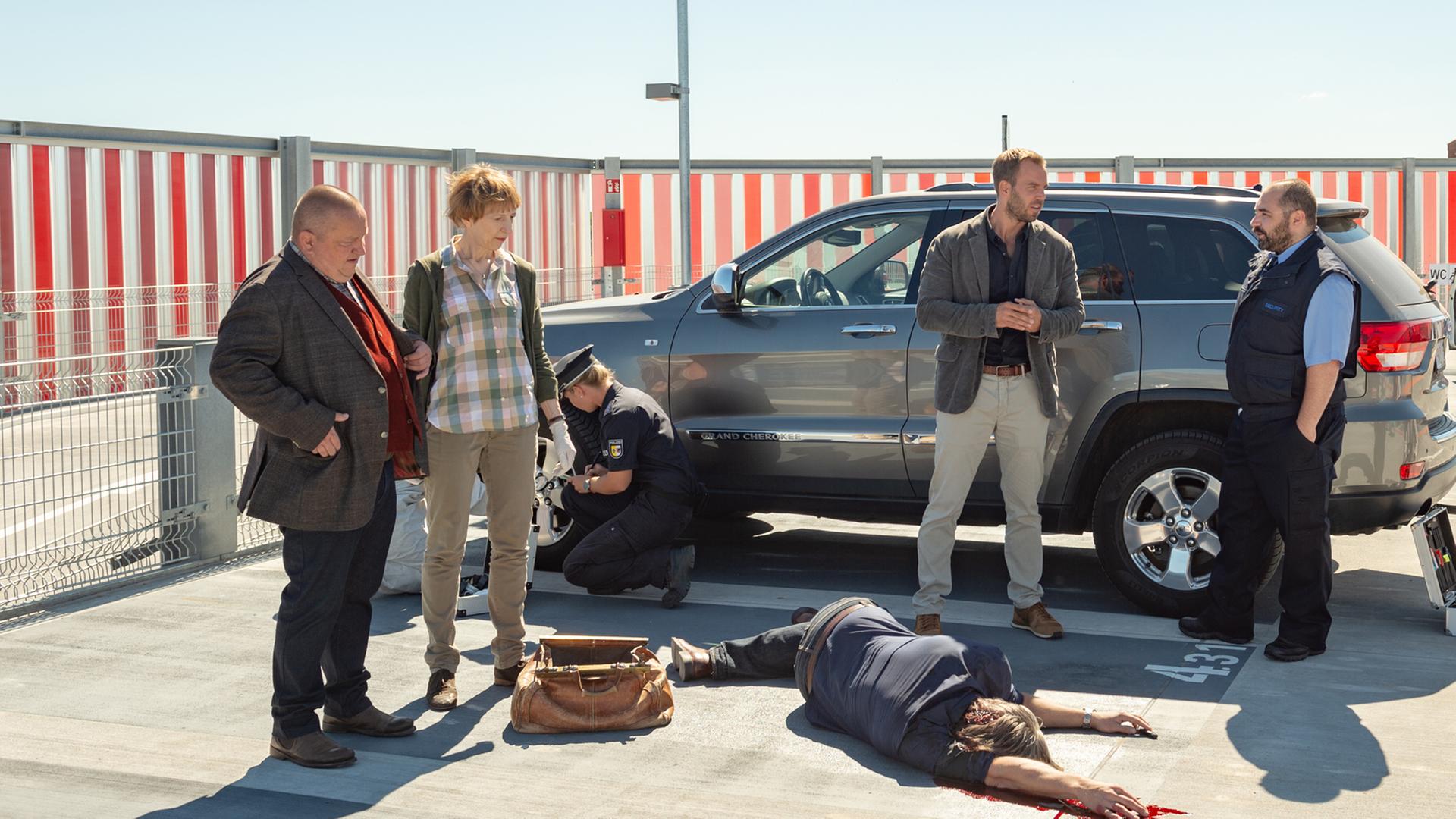 Reuter, Helene, Lars Pöhlmann, Stine und Maik Pohl stehen auf einem offenen Parkdeck rings um die Leiche von Gunnar Wittrock herum