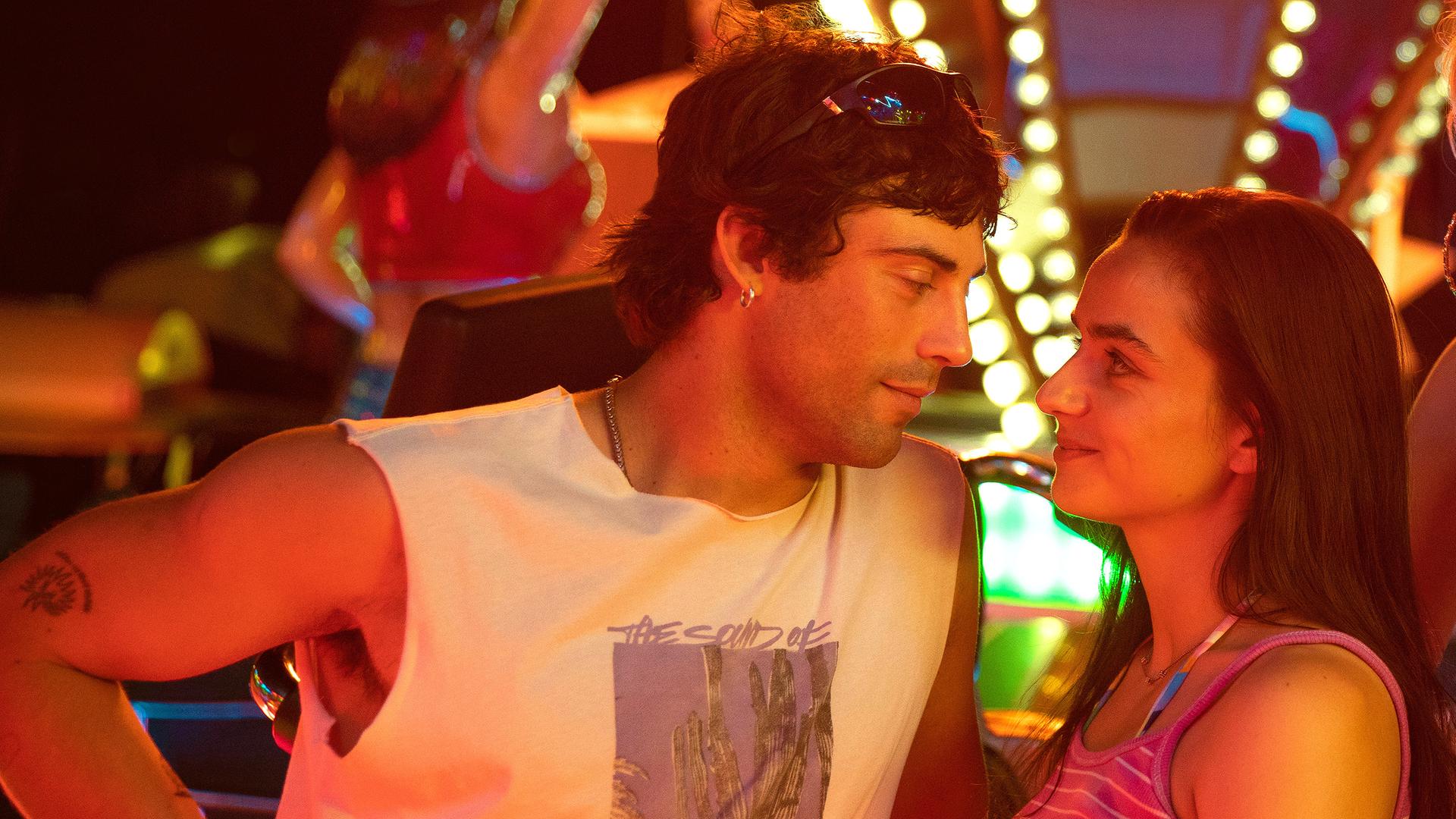 "Zwischen uns die Nacht": Erich (Aaron Altaras) und Marie (Laura Balzer) sehen sich in die Augen während Rebecca (Bea Brocks) und Haro (Paul Boche) in die Kamera sehen. Im Hintergrund leuchtet ein Fahrgeschäft bei Nacht.