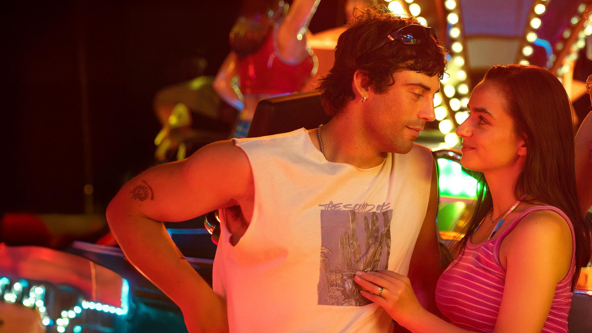 "Zwischen uns die Nacht": Erich (Aaron Altaras) und Marie (Laura Balzer) sehen sich in die Augen während Rebecca (Bea Brocks) und Haro (Paul Boche) in die Kamera sehen. Im Hintergrund leuchtet ein Fahrgeschäft bei Nacht.