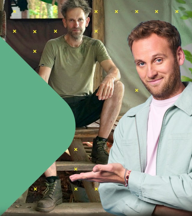 Dr. Leon Windscheid steht lächelnd im Vordergrund und zeigt zur Seite. Im Hintergrund sitzt Marc Freukes vor einer Holzhütte im Wald. Neben ihm liegt ein großer Stapel Brennholz.